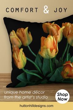 a black pillow with yellow tulips on it and the text, comfort & joy unique home decor from the artist's studio shop now