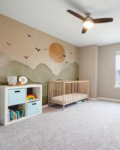 a baby's room with a crib, bookcase and mural on the wall