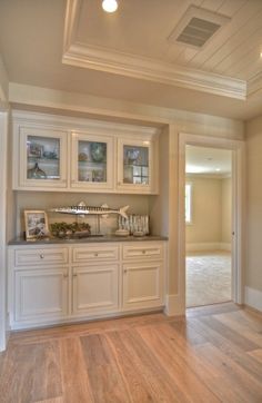 an empty kitchen with white cabinets and wood flooring in the middle of the room