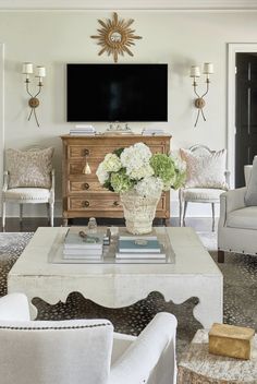 a living room filled with furniture and a flat screen tv mounted on the wall above a coffee table