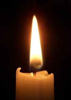 a lit candle in the dark with its light on