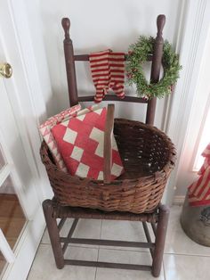 a basket with two red and white pillows on it sitting in front of a door