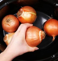 someone is holding onions in the slow cooker and they are ready to be cooked