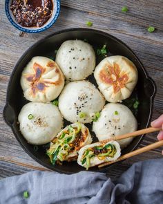 a pan filled with dumplings and chopsticks on top of a wooden table