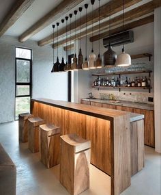 a bar with stools and bottles hanging from the ceiling in a modern style home