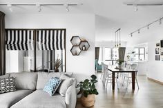 a living room filled with furniture next to a dining room table and windows covered in black and white striped curtains