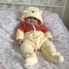 a baby in a winnie the pooh costume sitting on a bed