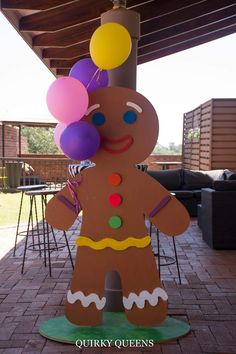 a large ginger holding balloons on top of a brick floored patio under a pergolated roof