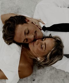 two people laying on the ground with their heads close to each other and one person touching his face