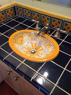 a sink that is sitting on top of a blue tile counter with orange and white tiles