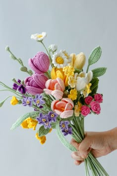 a person holding a bouquet of crocheted flowers