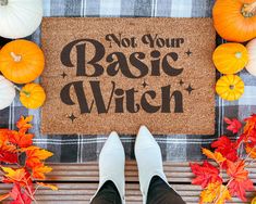 a welcome mat with the words not your basic witch on it surrounded by fall leaves and pumpkins