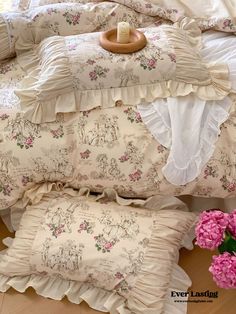 a bed with ruffled sheets and pink flowers on the headboard, along with two pillows