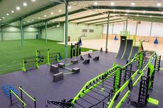 the inside of a gym with green and black equipment on the floor, lights overhead