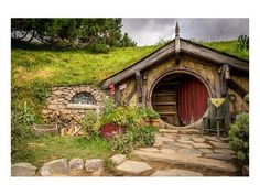 a hobbot house with a red door surrounded by greenery