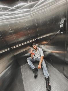 a man sitting on the ground in front of a metal wall