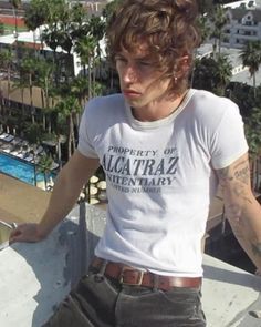 a man standing on top of a roof next to a swimming pool and palm trees