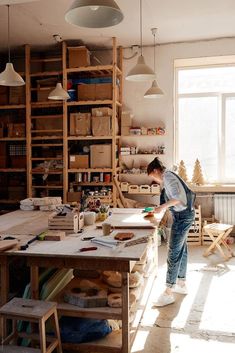 a man working in a workshop with lots of work on the table and shelves behind him