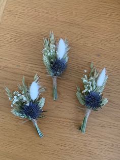 three bouquets of flowers sitting on top of a wooden table next to each other