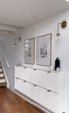 a white dresser sitting in the middle of a living room next to a stair case