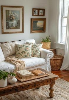 a living room with white couches and pictures on the wall above them, along with potted plants