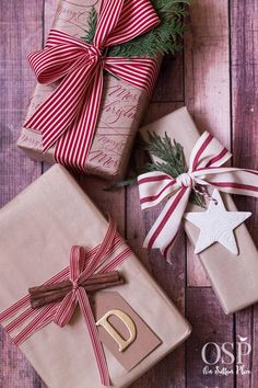 presents wrapped in brown paper with red and white ribbons tied around them on a wooden surface