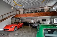 two cars are parked in a garage with stairs leading up to the second floor and another car is on the other side