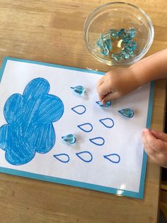 a child's hand is drawing on a piece of paper with blue crayons