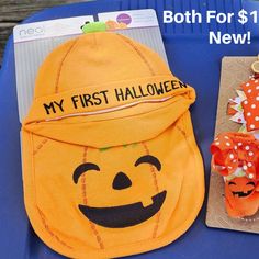 a child's pumpkin hat and other items on a blue table with the words my first halloween next to it