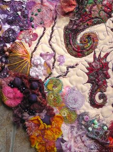 a large piece of art made out of fabric and other things on the ground with beads