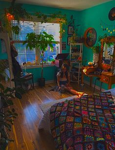 a woman sitting on the floor in a bedroom next to a bed with a colorful bedspread