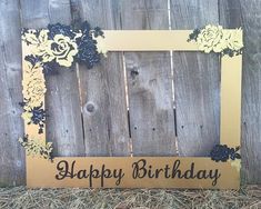 a happy birthday sign sitting on top of hay next to a wooden fence with flowers