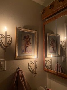 two framed pictures hang on the wall next to a couple's photo and candles