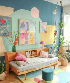 a living room filled with lots of furniture and colorful paintings on the wall above it