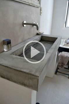 a bathroom with a concrete sink in the middle and a mirror on the wall above it