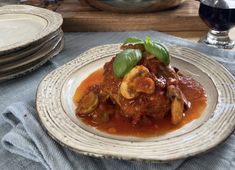 a white plate topped with meat and vegetables covered in sauce on top of a blue table cloth