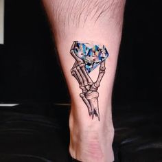 a tattoo on the foot of a person with a blue diamond in it's hand