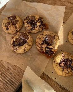 several chocolate chip cookies sitting on top of brown paper