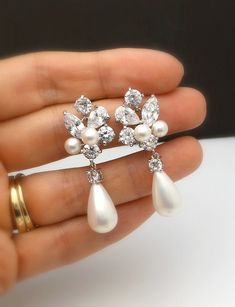 a person is holding some kind of brooch with pearls and diamonds on it in their hand