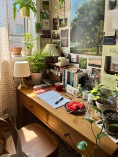 a wooden desk topped with lots of plants next to a window covered in books and pictures