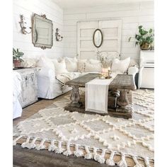 a living room filled with white furniture and lots of pillows on top of a rug