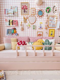 a room with pink walls and lots of pictures on the wall above the couch is filled with toys