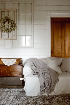 a living room with a white couch and wooden cabinet next to it on top of a rug