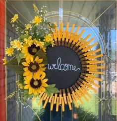 a welcome sign with sunflowers and greenery in front of a glass door