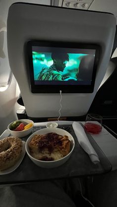 a tray with food and drinks on it in front of a television screen that is turned on