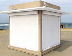 a small white building sitting on top of a cement ground next to the ocean and sky