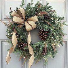 a christmas wreath with pine cones and burlocks hanging on the front door,