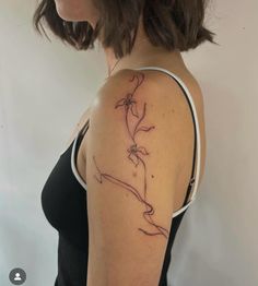 a woman's arm with a flower tattoo on the left side of her shoulder