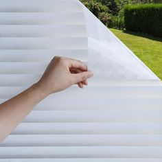 a hand is holding up the blinds outside