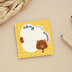 there is a note with a bear on it next to some pencils and a basket